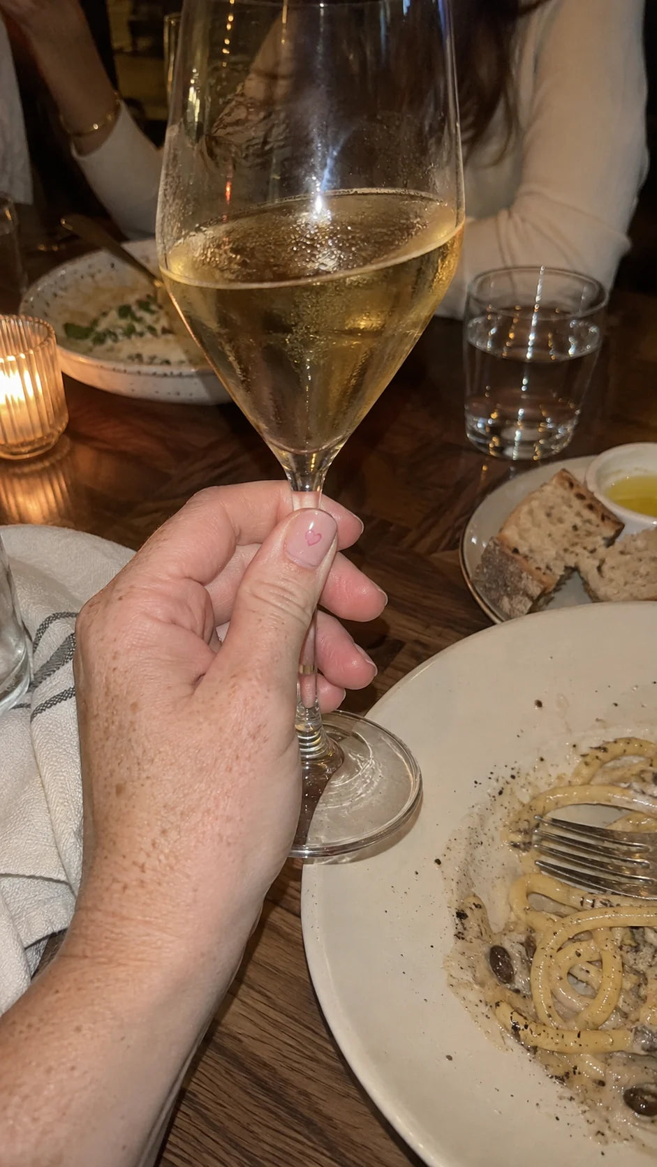 A hand beside a drink at dinner, from the Lilac Signal brand journal