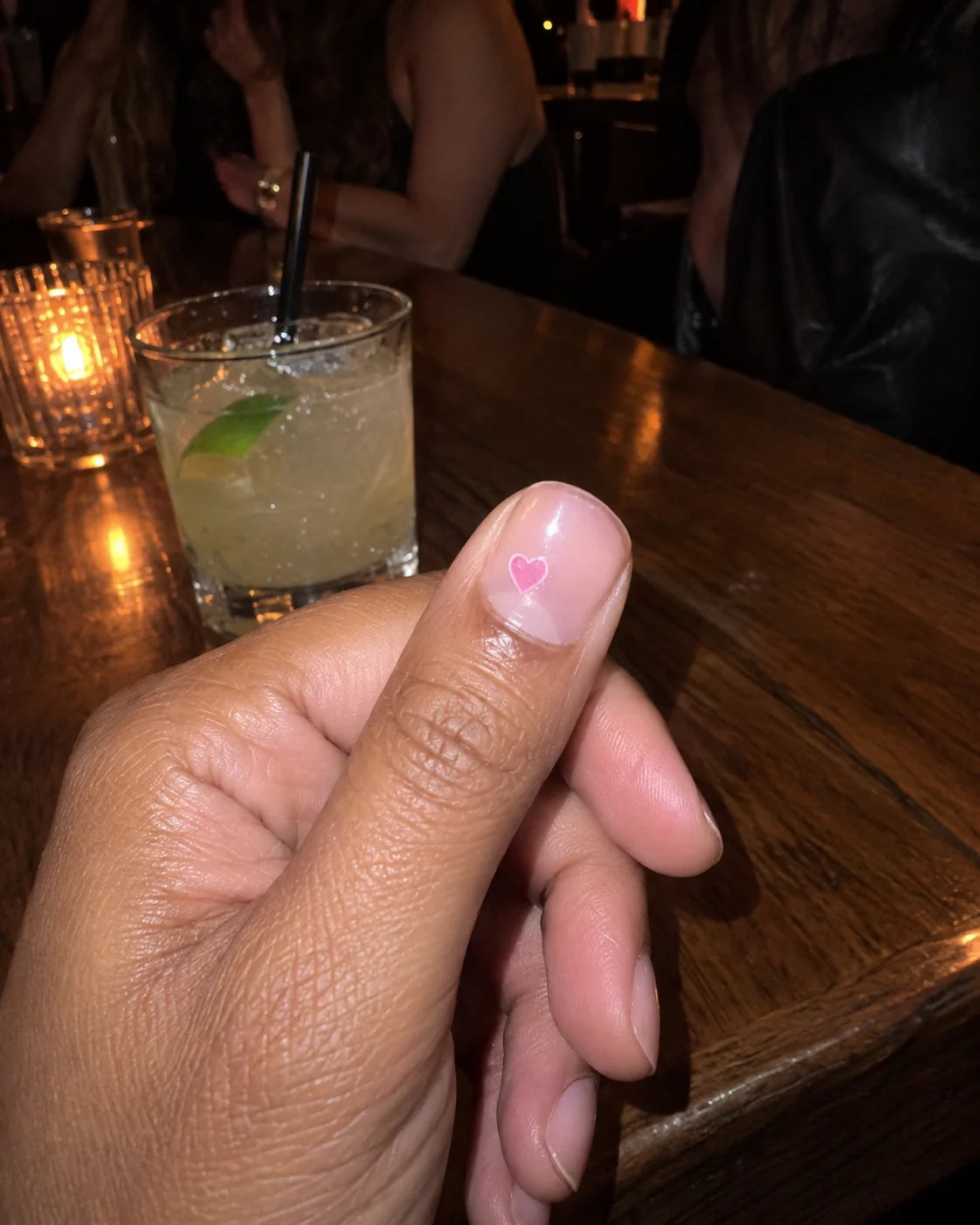 A close-up of a small heart nail sticker beside a drink, from the Lilac Signal brand journal
